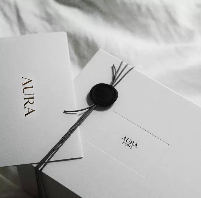 A minimal white Dior gift box with elegant black string and wax seal rests beside a matching card, creating a luxurious and refined presentation aesthetic.